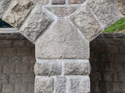 Rough granite stone wall of large blocks set in light gray mortar, close up view Stock Photos