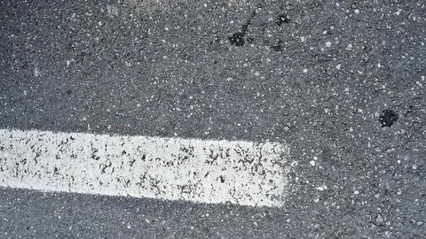 Rough gray asphalt road surface with a crisp white painted line Stock Photos