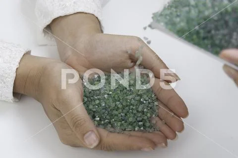 Rough green Peridot gemstone in hand on white background. Stock Photos