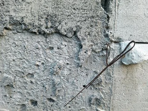 Rough grey concrete wall texture featuring weathered cracks and metal Stock Photos