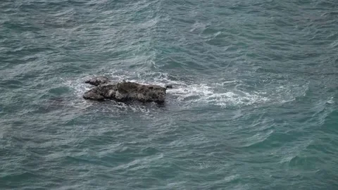 A rough large stone is washed by water in the ocean, small waves on the sea Stock Footage 202120179