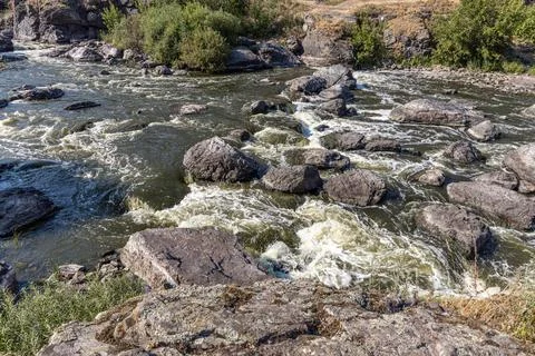 Rough mountain river flows among stones in summer day Stock Photos