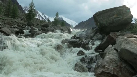 Rough mountain river is rushing between the big rocks in a sunny weather Stock Footage 73349689