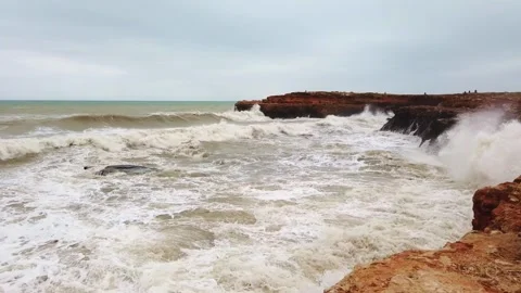 Rough Ocean Waves Crashing Against Rugged Reddish-Brown Rocky Coastline Video stock 342126742