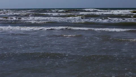 Rough ocean waves rolling across dark seawater under calm blue sky on open Stock Footage 346558995
