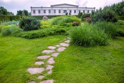 Rough ornamental stone path paved in green lawn on park walkway landscaped. Stock Photos