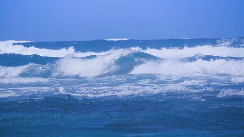 Rough seas with waves crashing in slow motion under a blue sky Vídeo Stock 87703078