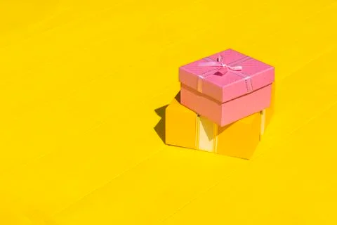 Rough shadow. Bright sunshine. Retro yellow wooden background. Gift box in pi Stock Photos