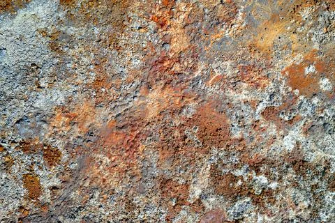 Rough stone surface with spots of rusty red and grey. Colorful texture in old Foto stock