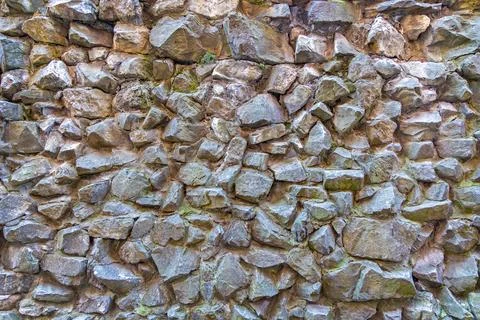 Rough stone wall made of irregular rocks. Close-up of a rugged stone wall built Stock Photos