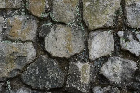 Rough stone wall with mossy, weathered surfaces Stock Photos