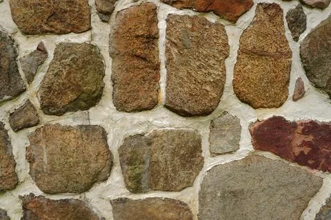 Rough stone wall texture with irregular multi-colored rocks mortared together 写真素材