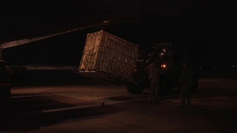 Rough terrain forklift unloads container from a C-130 at night 1 Stock Footage 112127757