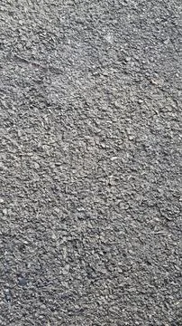 Rough textured asphalt surface with small stones and cracks. Stock Photos
