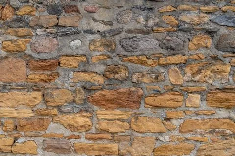 Rough textured stone wall with varied colors and irregular shapes Stock Photos