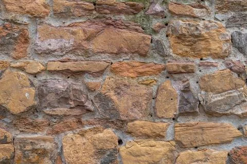 Rough textured stone wall with varied colors and irregular shapes Stock Photos