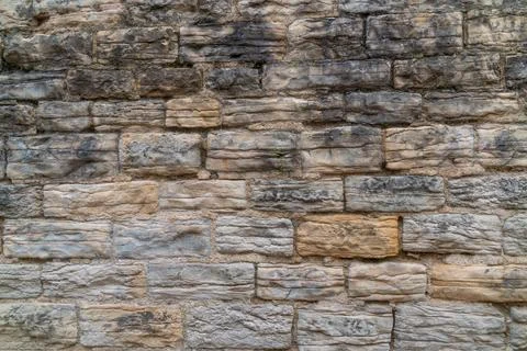 Rough textured stone wall with varied colors and irregular shapes Stock Photos