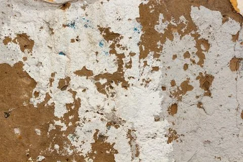 Rough textured wall with peeling white paint and exposed brown concrete surface Fotos de archivo