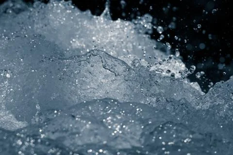 Rough water with splashes on a black background Stock Photos
