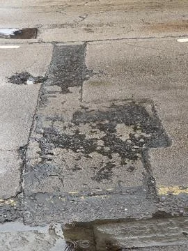 Rough, weathered texture of dark patch asphalt repair. Stock Photos