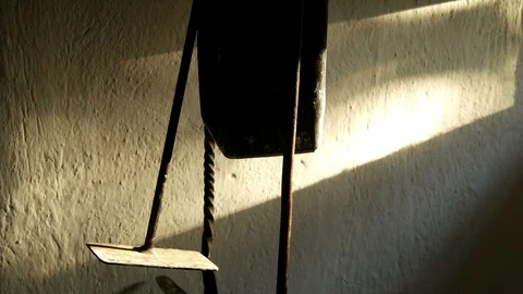 Rough white plaster wall &amp; hanging iron tools lit by flickering sunlight shaft Vidéo 122865083
