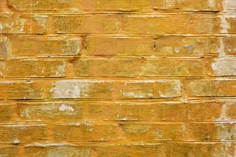 Rough yellow brick wall with peeling paint. texture for background Stock Photos