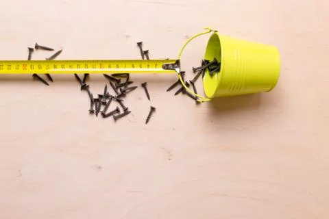 Roulette measuring pulling a bucket of nails. Still life. Stock Photos
