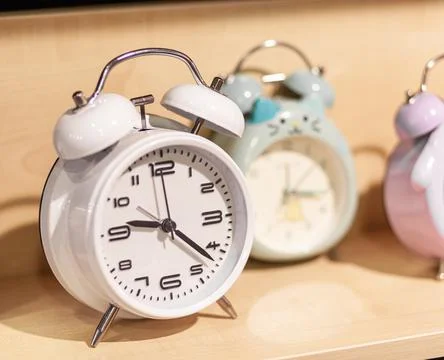 Round alarm clock on the store shelf close-up. Sale of various watches Stock Photos