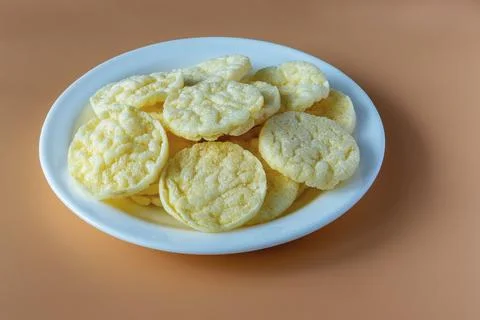 Round and crispy rice crackers on a white plate isolated on a beige backgroun Stock Photos