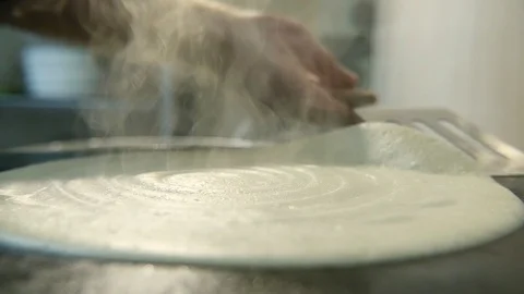 A round and flat pancake cooking. A hand witha a spatula raises it in slo-mo Stock-Footage 86594300
