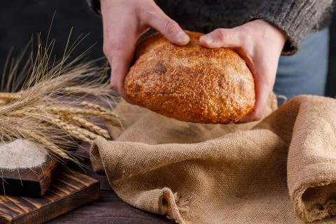 Round artisan bread closeup in a man's hand. The concept of healthy food and  Stock Photos