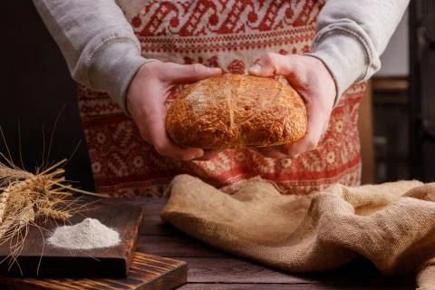 Round artisan bread in the hands of a baker. The concept of healthy food and tra Stock Photos
