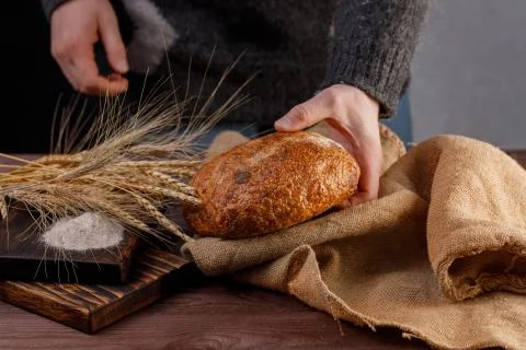 Round artisan bread in the hands of a man close-up. The concept of healthy fo Stock Photos