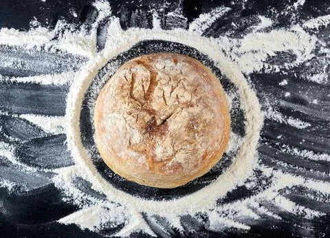 Round baked bread and white wheat flour scattered Stock Photos