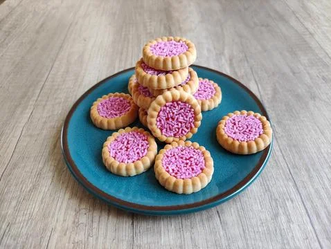 Round baked sweet biscuits with bright red filling and pink pastry sprinkles Stock Photos