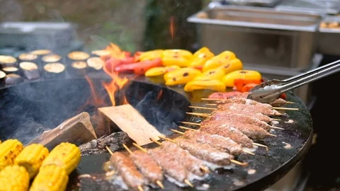 Round barbecue grill with open fire inside. Meals for summer picnic are being Stock Footage 114694521