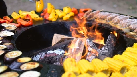 Round barbecue grill with open fire inside. Meals for summer picnic are being Stock Footage 114694611