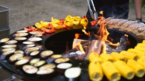 Round barbecue grill with open fire inside. Meals for summer picnic are being Stock Footage 114694768
