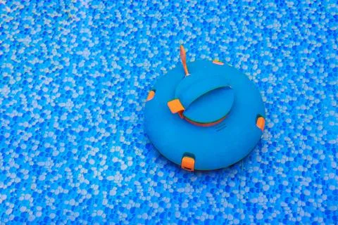 Round blue pool robotic vacuum with orange details sits in surface of clear b Stock Photos