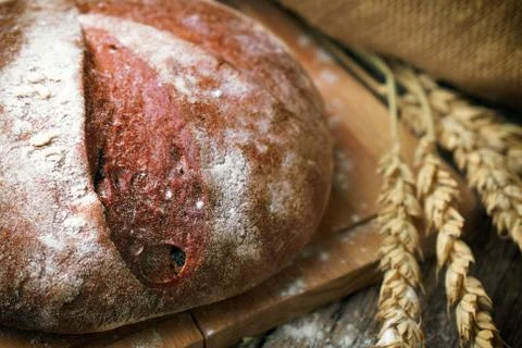 Round bread and wheat ears on the old wooden table 写真素材