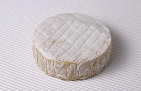Round Brie cheese with a sections cut out over white corrugated background. Foto stock