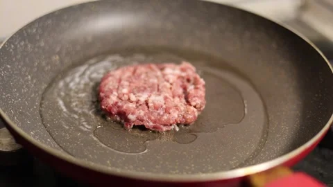 Round burger patty of ground beef is fried in sunflower oil Stock Footage 332574120