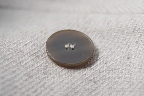 Round button lies on light fabric surface Stock Photos
