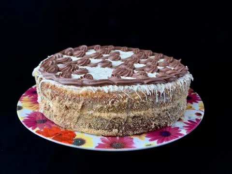 Round cake with cream patterns, on a black background. A sweet birthday prese Stock Photos