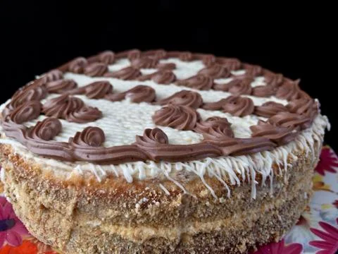 Round cake with cream patterns, on a black background. A sweet birthday prese Stock Photos