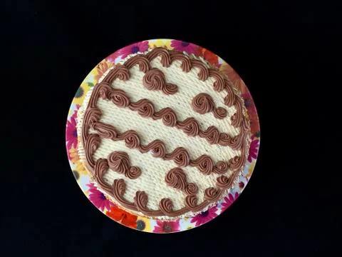 Round cake with cream patterns, on a black background. A sweet birthday prese Stock Photos