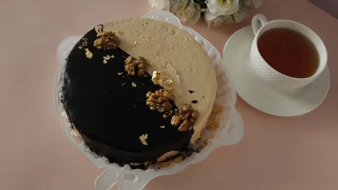 Round cake in a plate, a mug of tea and a teapot on a pink table. Tea drinking Stock Footage 324782552