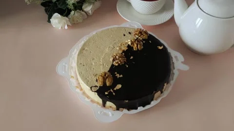 Round cake in a plate, a mug of tea and a teapot on a pink table. Tea drinking Stock Footage 324782611
