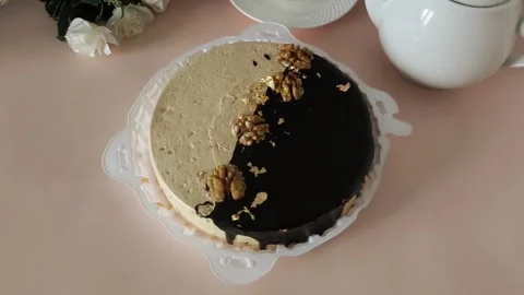Round cake in a plate, a mug of tea and a teapot on a pink table. Tea drinking Stock Footage 324782640