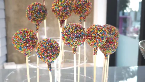 Round cake pops covered in multicolored sprinkles on wooden sticks Stock Footage 283401118